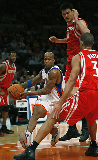 New York Knicks guard Stephon Marbury (L) drives by Houston Rockets center Yao Ming (rear) and forward Shane Battier (R) in the first period of their NBA basketball game in New York November 20, 2006. 