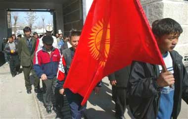 Kyrgyz protesters carry a national flag as they enter a police station taken during Monday's protests, in Osh, Kyrgyzstan's second-largest city, Tuesday, March 22, 2005. About 100 opposition protesters wearing yellow ribbons were gathered in the central square in Osh on Tuesday. President Askar Akayev told Kyrgyzstan's newly elected parliament on Tuesday that the opposition was using protests to destabilize the Central Asian nation but that he would not impose a state of emergency. (AP