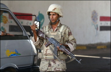 An Iraqi soldier gestures to a vehicle at a checkpoint set-up along a highway leading south out of Baghdad. At least 20 former police commandos were killed and 100 wounded in a double suicide bombing outside government offices in Hilla, south of Baghdad(AFP