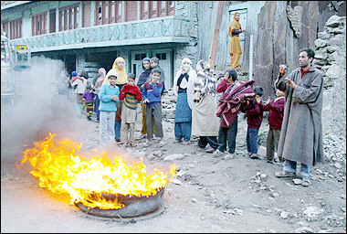 Indian Kashmiri residents warm themselves by burning tires after their homes were damaged by a 7.6 magnitude earthquake two days before, in Uri, some 110 kms from Srinagar.