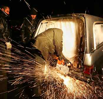 A police officer uses a special cutting machine to free anti-nuclear protesters who chained themselves on a concrete block and the chassis of a former hearse in the small village of Grippel late November 21, 2005, as they block the transport road to the Gorleben interim storage facility.