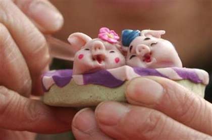 A man makes a sculpture of pigs at a temple fair in Shenyang, northeast China's Liaoning province, February 13, 2007. 